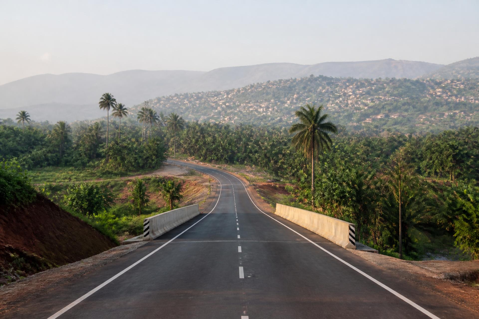 A newly paved road winding through the green hills of Sierra Leone at sunrise